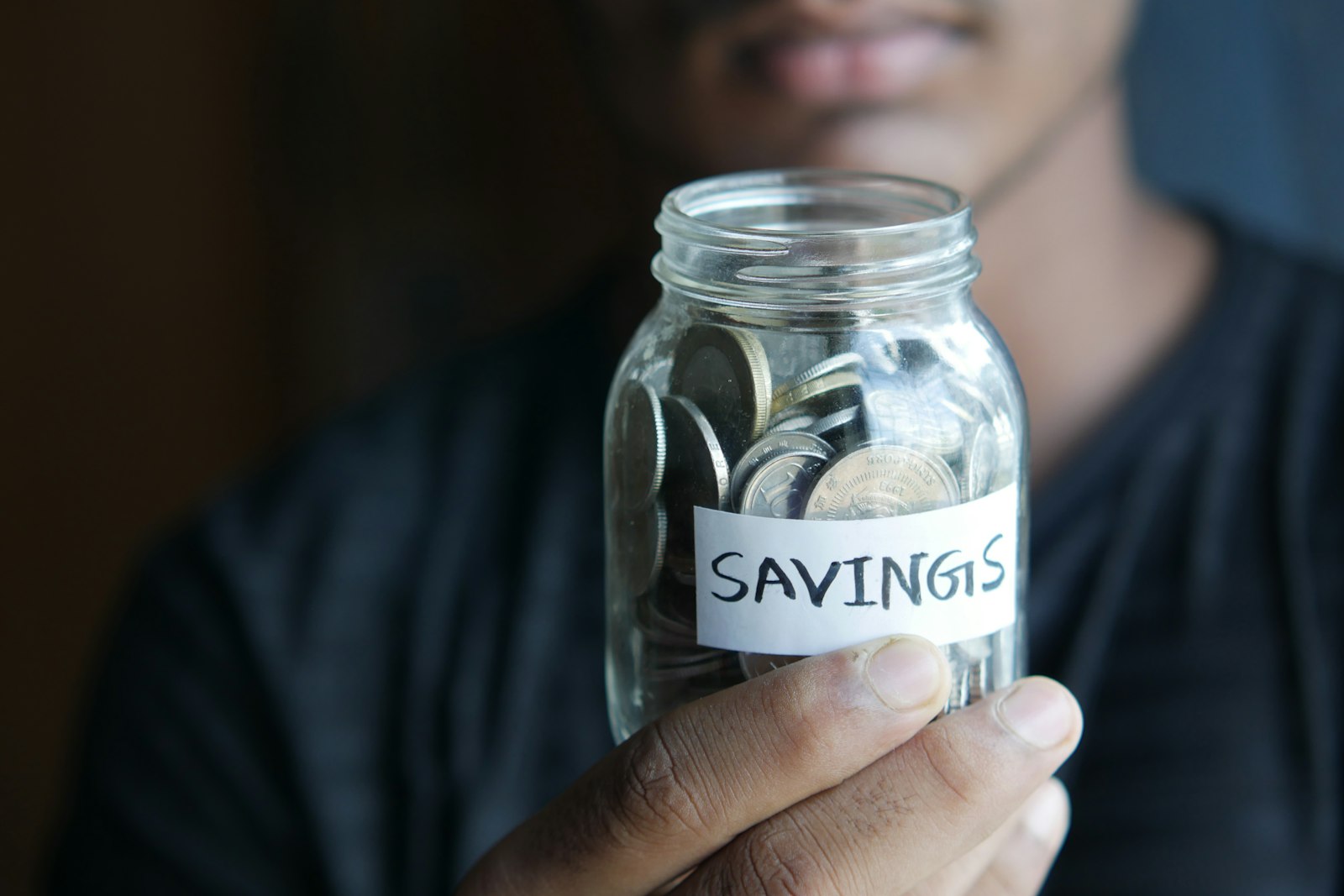 A person holding a glass jar labeled savings