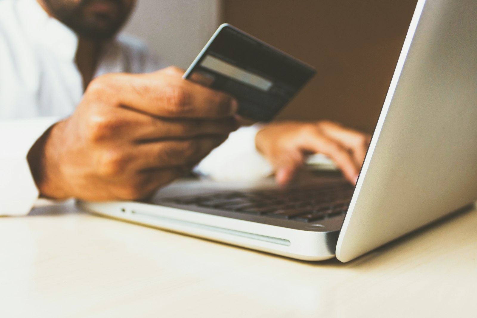 A person holding a credit card while using a laptop