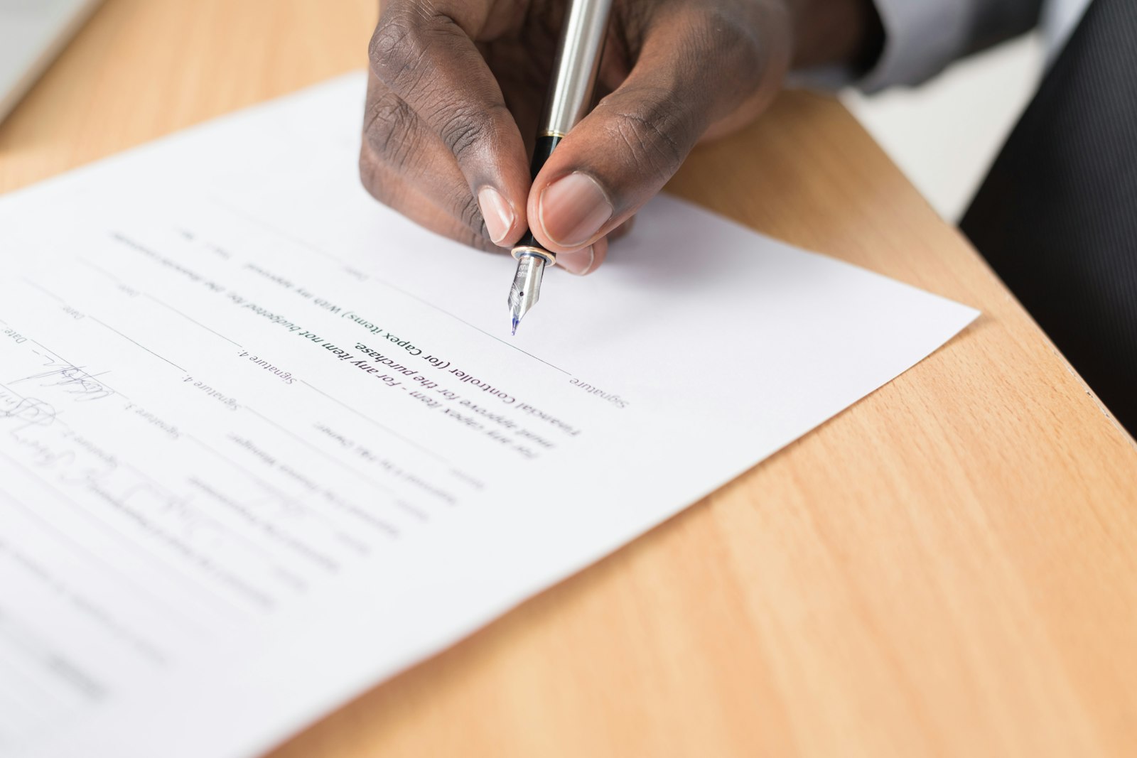 A person signing a document with a pen