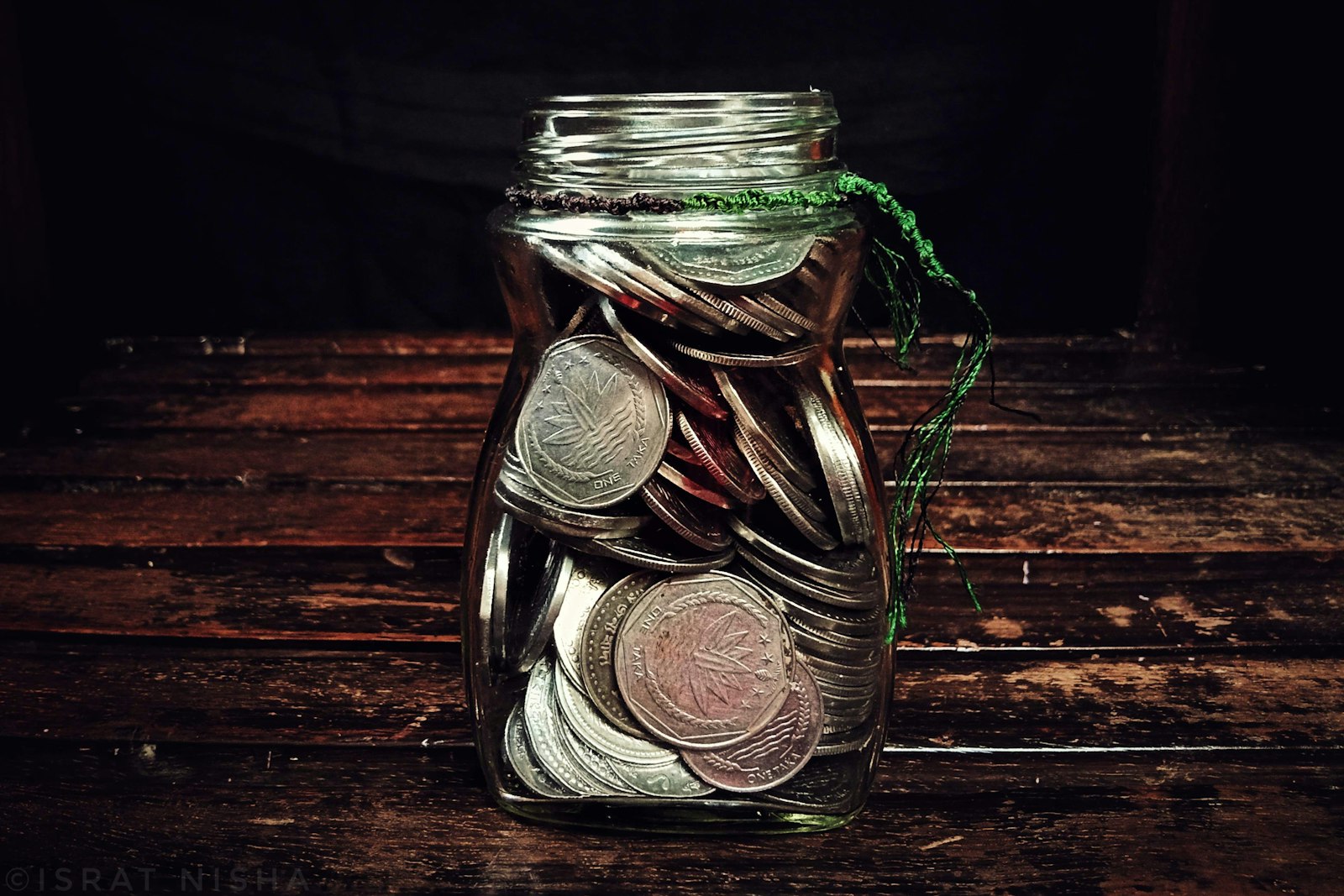 A glass jar of coins on a wooden table